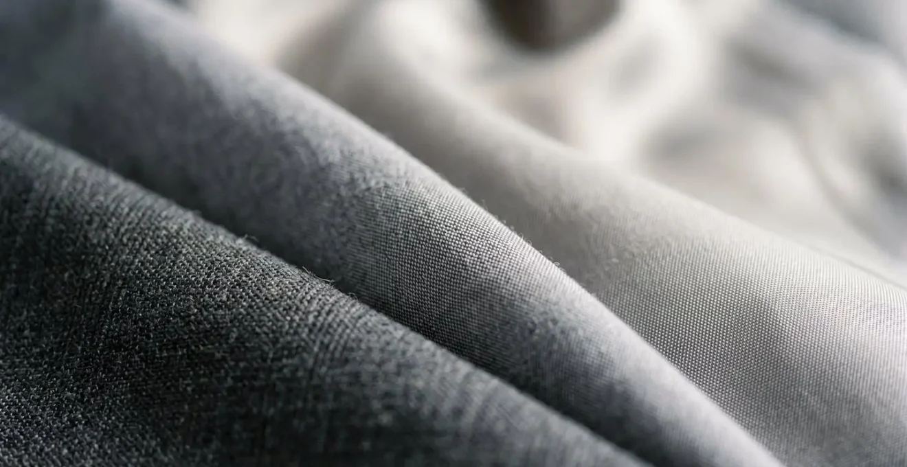 Extreme close-up macro shot of layered professional fabrics in tonal shades revealing intricate textile textures and subtle color variations